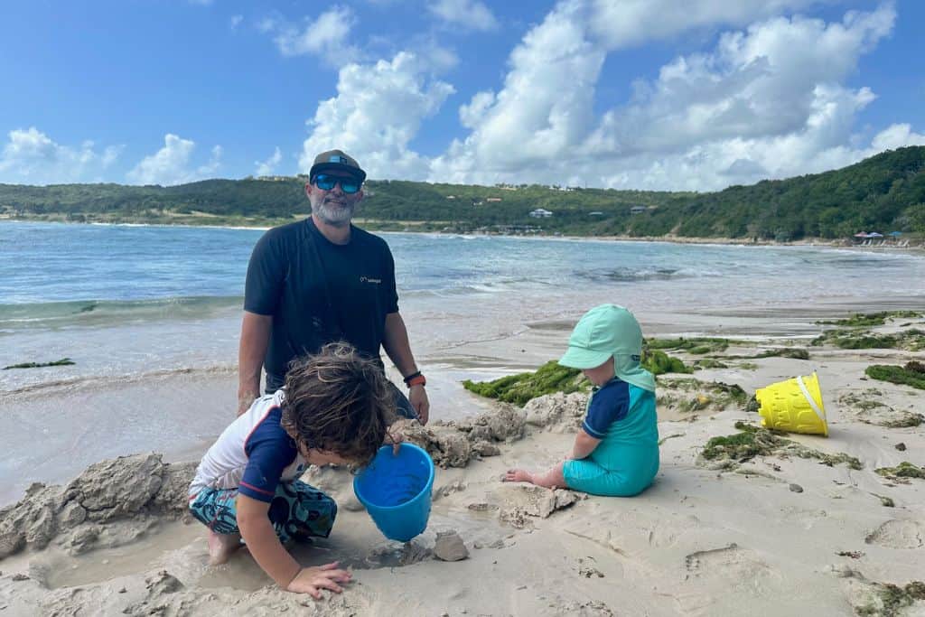 dad on a beach in Antigua with his baby and toddler sons