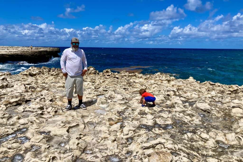 Father and son stood on the edge of Devil's Bridge in Antigua