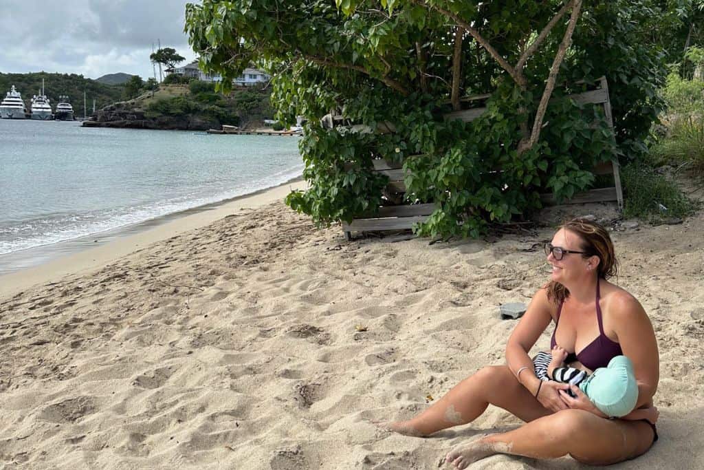mum on a beach with her baby asleep on her in Antigua