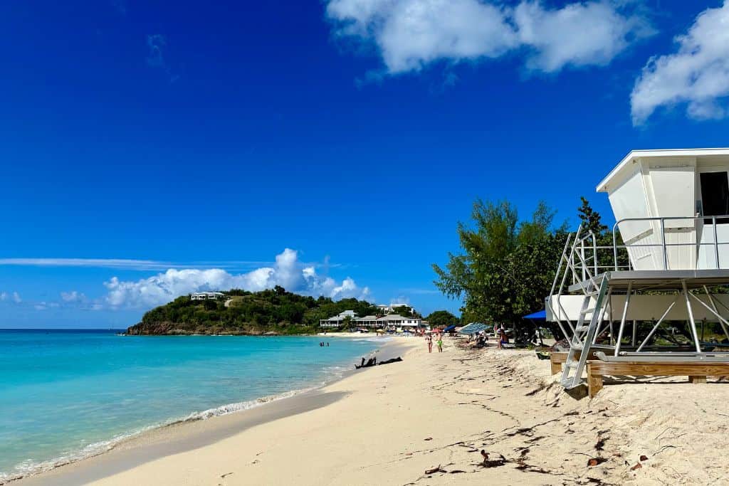 A safe beach in Antigua which is safe to swim at as it has a lifeguard tower with blue skies and golden sands