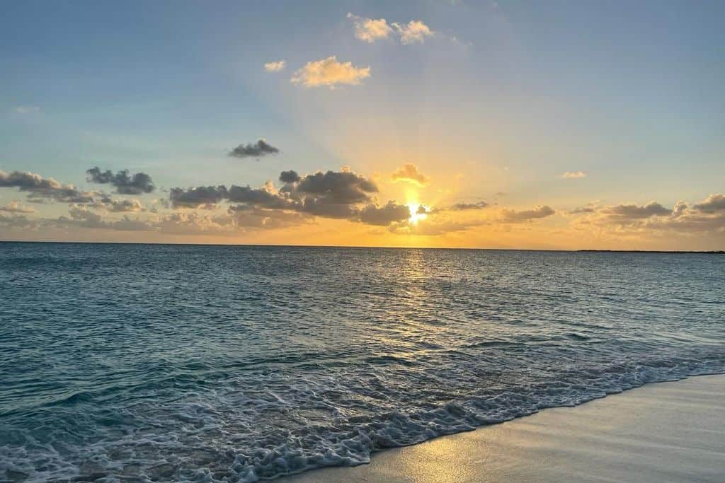 Princess Diana beach in Barbuda with the sun setting on it.  The sand is white and the sky is in the golden hour and lots of wonderful golden colours.