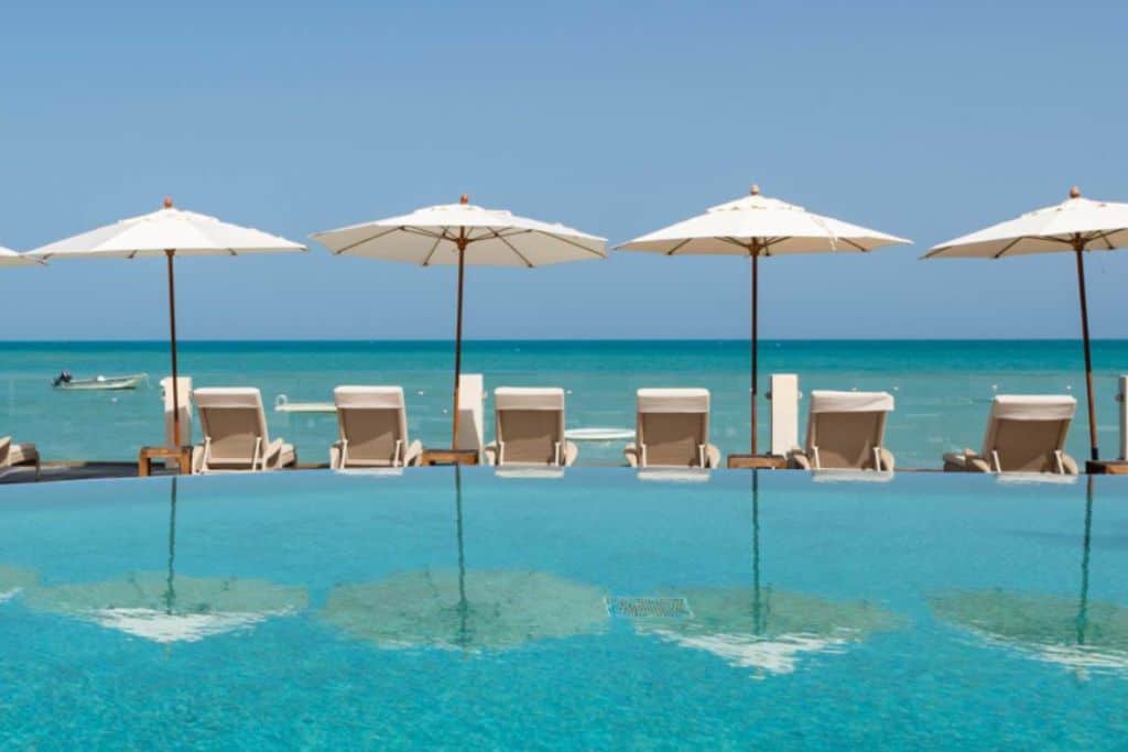 Parasols at the edge of a swimming pool at Blue Waters Resort which is one of the best Antigua all inclusive family resorts.