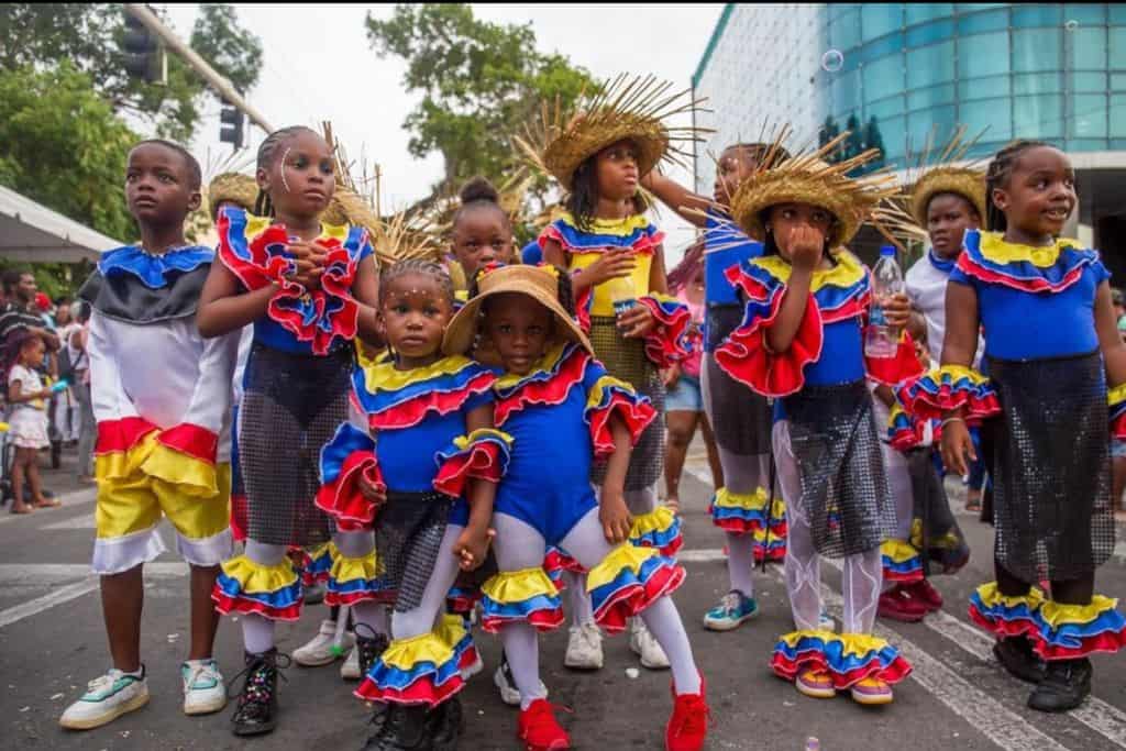 A large group of local children in the Junior Carnival Parade outfits of blue and red at Antigua Carnival
