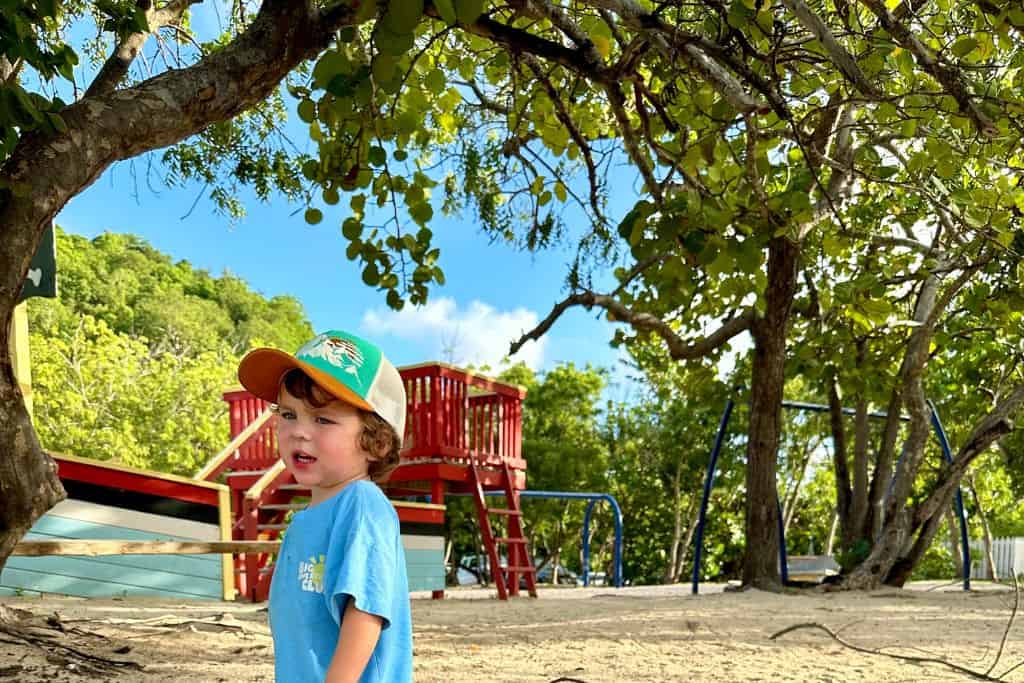 Boy in front of playground at Pigeon Point Beach in English Harbour, Antigua