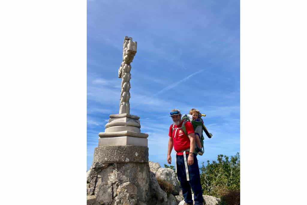 A man with his son on his pack in the park at Pena Palace at the cross which is the highest point in the park. Pena Palace is sintra castles