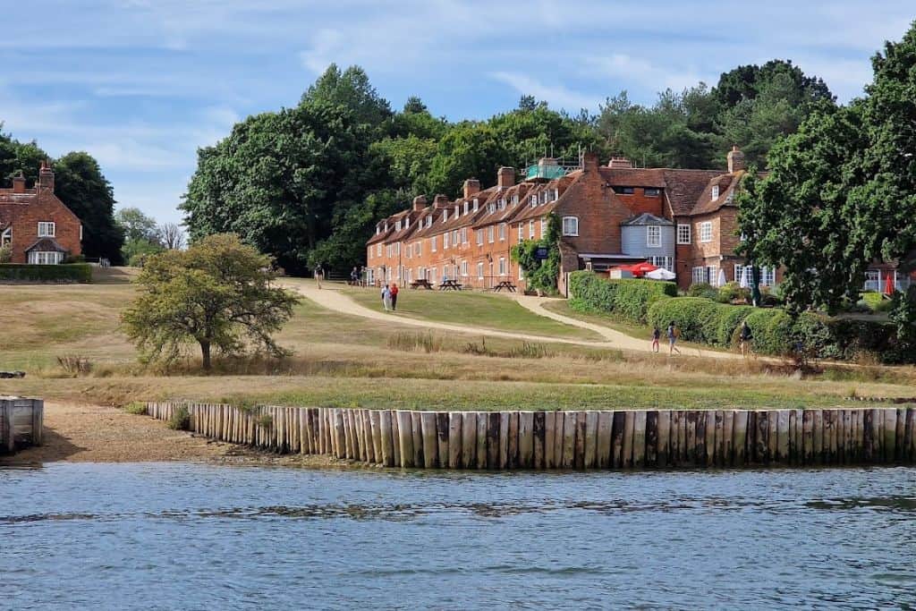Beaulieu River with large grass area with some building into the left which is Bucklers Hard in the New Forest.