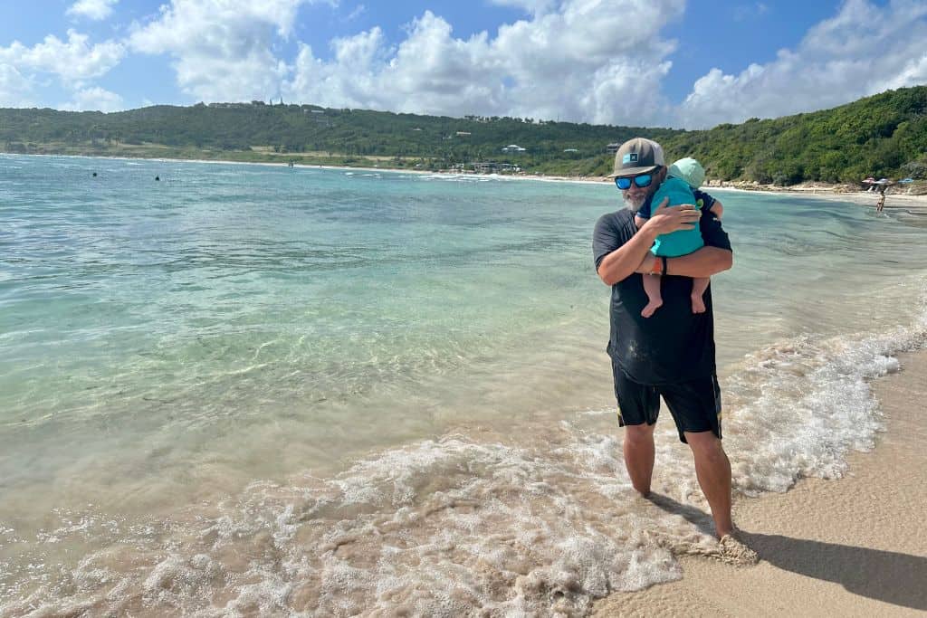 Father holding his son on the beach at Half Moon Bay.  This is near the best snorkelling in Antigua spot by the rock wall.