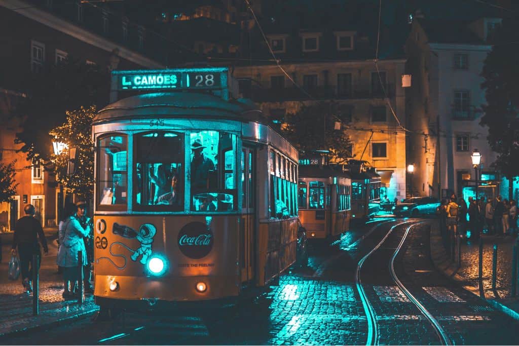 The tram 28 driving through the Barrio Alto district in nightime wiht the lights lit up. Barrio Alto is the best area to stay in Lisbon for night owls.