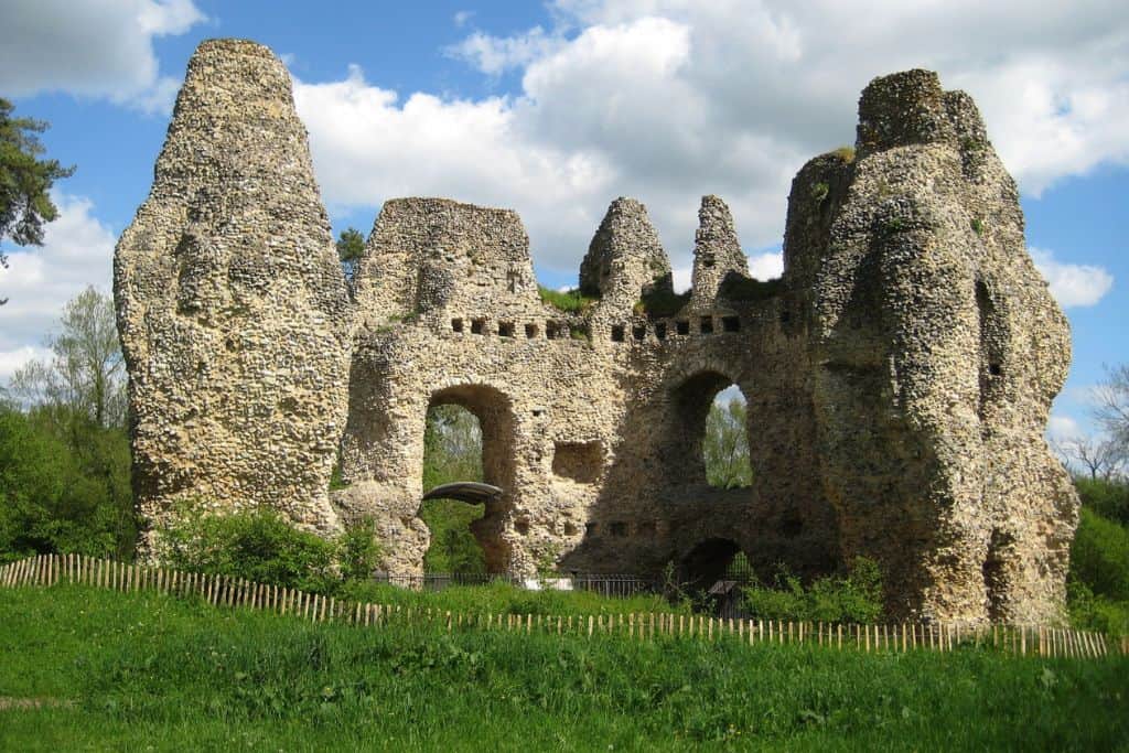 The ruins of Odiham Caste with green grass in front. There are blue skies with white clouds.