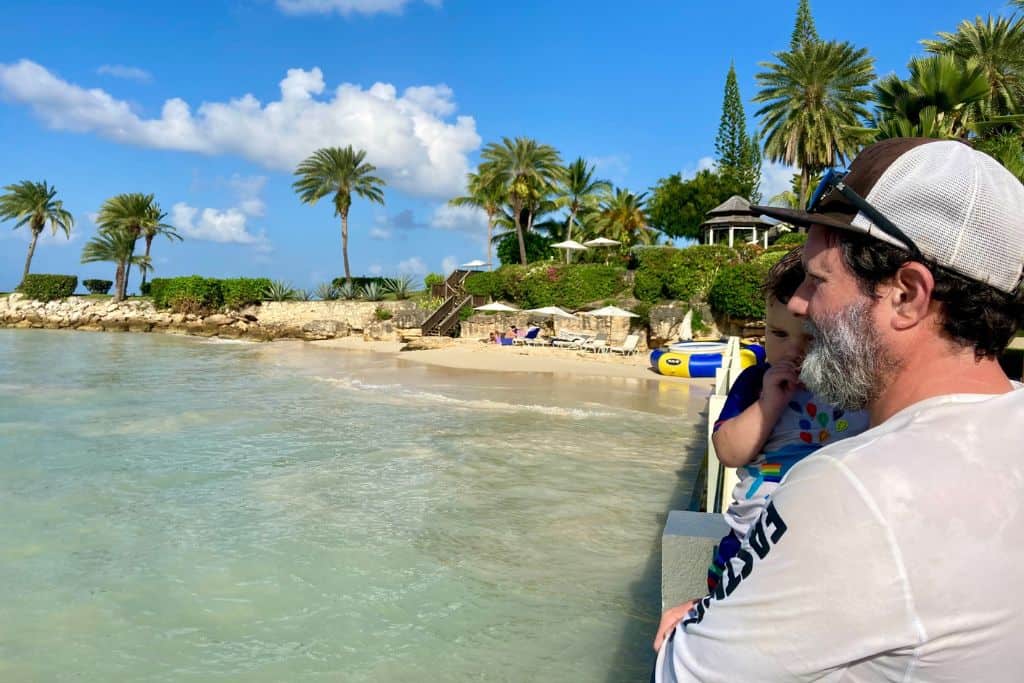 A father and son looking out over the beach at Blue Waters Resort in Antigua.