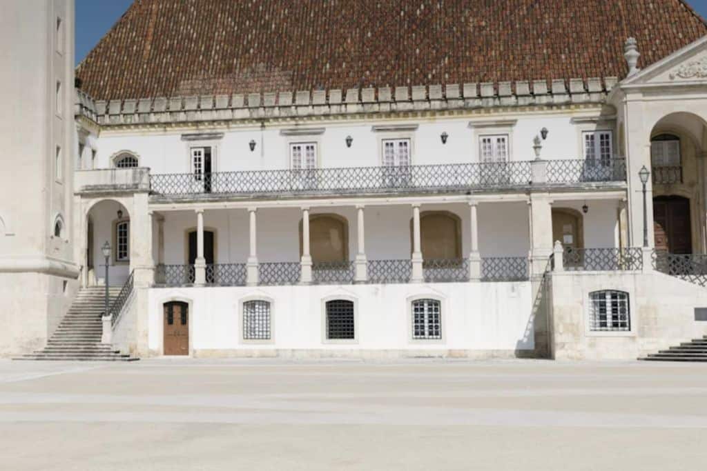 The white outside of the university building of Coimbra in Portugal.  Around it are two balconies.