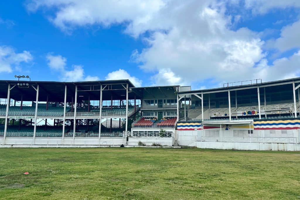 The old seating area of the Old Recreation cricket ground in St John's which is the Antigua cruise port..  There is lush green grass in the foreground of the seating area.