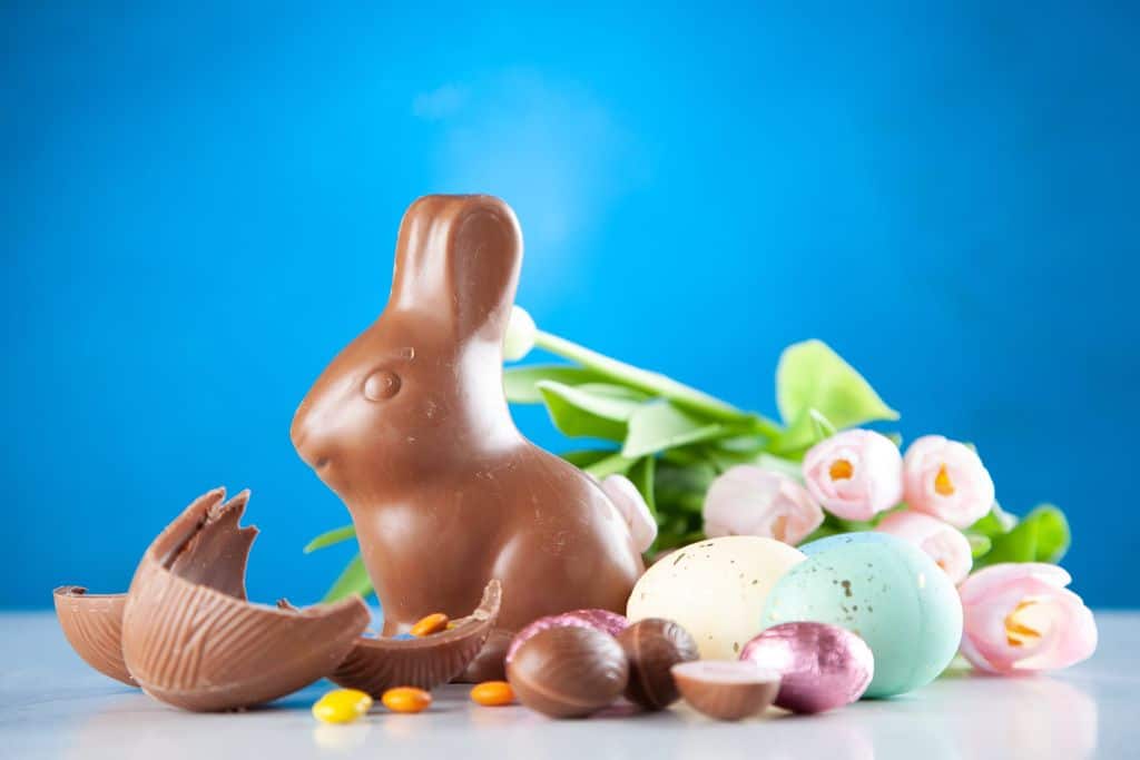 Display of a chocolate rabbit, a broken chocolate Easter eggs with some smaller Easter eggs and small chocolate sweets surrounding it.