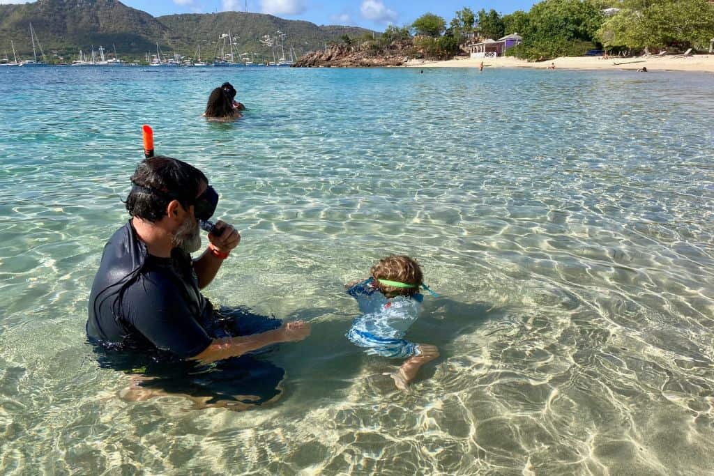 Father and son in the water close to the beach at Galleon Bay where the boy is learning to snorkel.  Galleon Bay is one of the best places in Antigua for snorkelling.