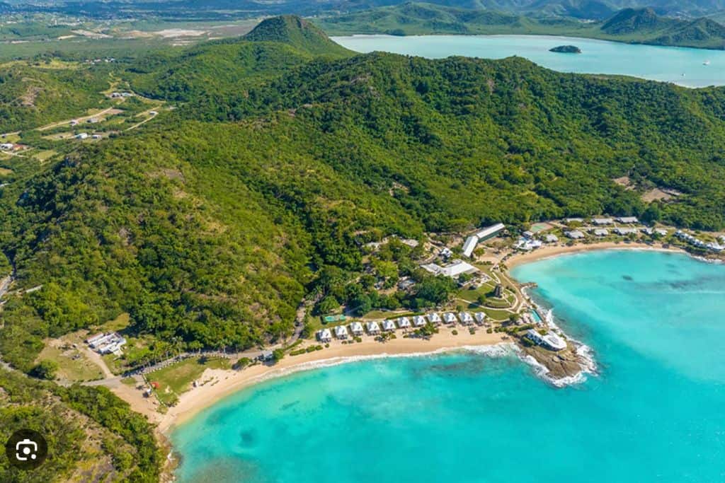 A view above the Hawksbill Resort where you can see 2 of the four beaches at the resort. There are also lush green rainforests that are in the hills above the beach.