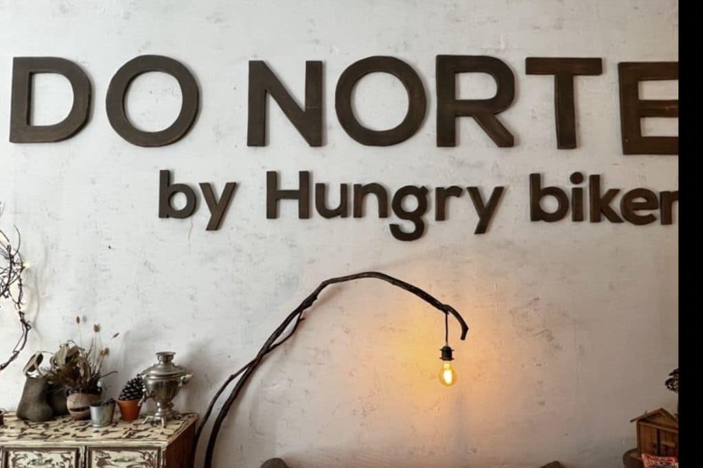 Beige wall with Do Norte by Hungry Biker sign on it with lamp nest to the sign.