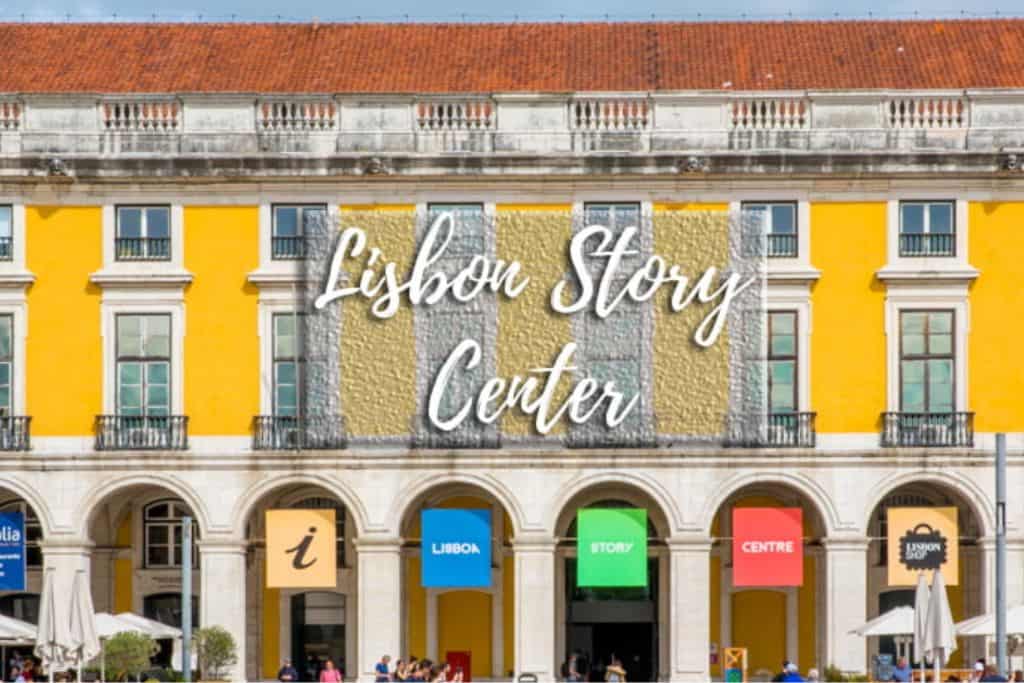 The outisde of the Lisbon Story Centre which has a yellow facade with a large sign with its name on.  There are people sat at small cafe tables outside it.