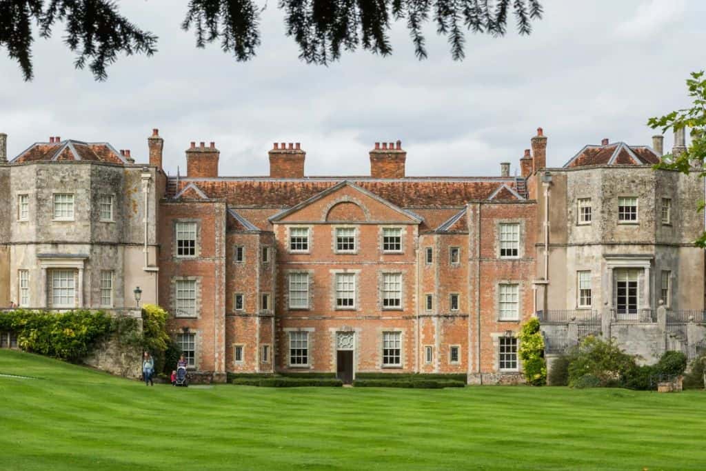 The outside of Mottisfont House in Romsey.  The facade is made up of a combination of red earthen bricks and lighter coloured grey cut stone bricks.