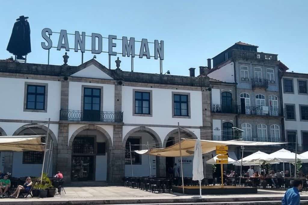 The outside of the Sandeman building in Porto Portugal which is white with a large sign saying Sandeman above it. Sandeman is one of the best winteries in Porto Portugal