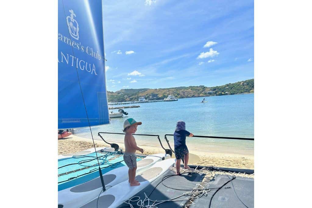 Two boys playing on a Hobie Cat on the beach at St James Club and Villas.  One of the best Antigua all inclusive luxury resorts for families.