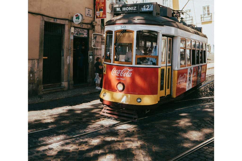A yellow tram going along the road in Lisbon which is usually on most peoples Portugal bucket list.
