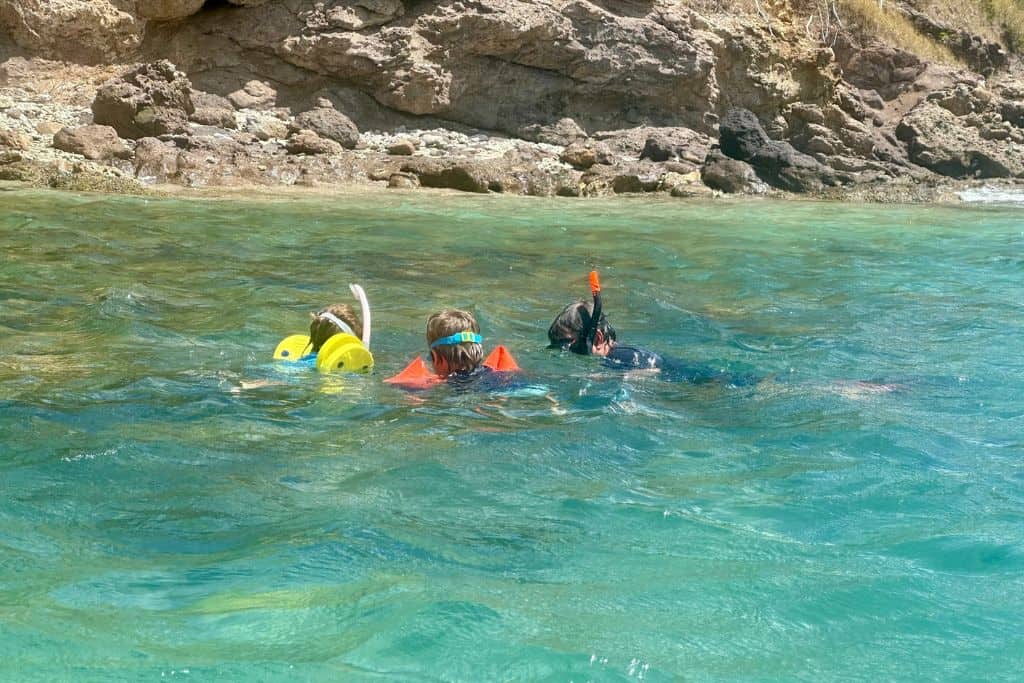 A man is in the water snorkelling with two young kids in Antigua.