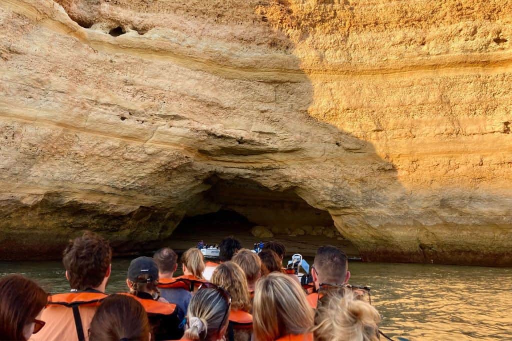 The view is of the back of a tour group that are sat on on a boat looking at the Benagil sea cave that they are about to enter. The Benagil sea cave is famous in the Algarve in Portugal and is one of the most popular things you can do with kids. 