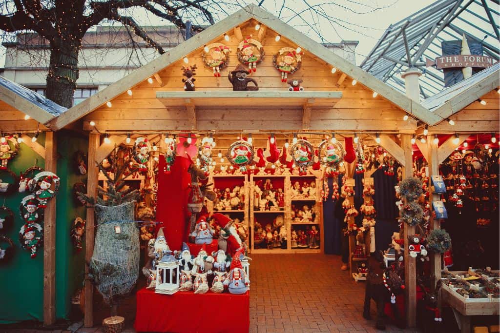 The front of a small shopping chalet at the Christmas Market in Porto in Portgual which opens in November.  On the shelves are lots of different Christmas decorations up for sale such as santa tree decorations and mrs claus sat in a door wreath.