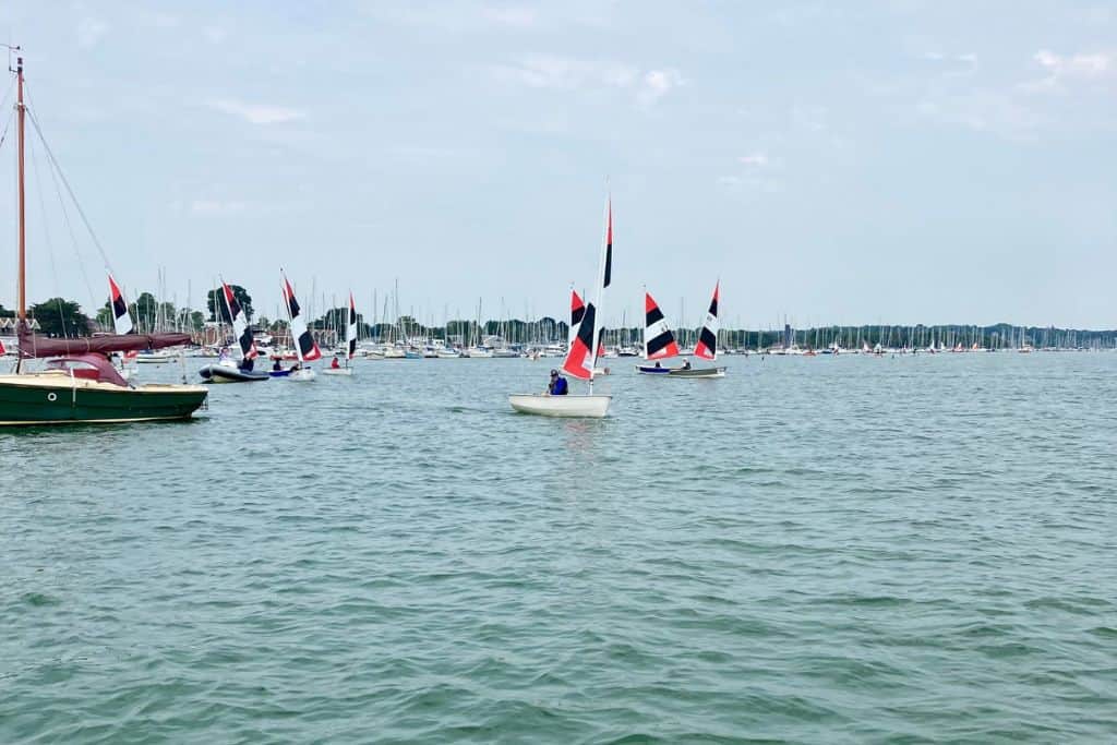 This is an image of the River Hamble and on it are lots of small dinghies all racing each other.  The dinghies have red and black sails.