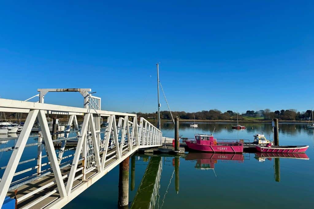 There is a white footbridge on the left of the image that is there to take people down to a floating pontoon on the River Hamble. Parked alongside the pontoon is the pink ferry that takes people from Hamble Le Rice over to Warsash.