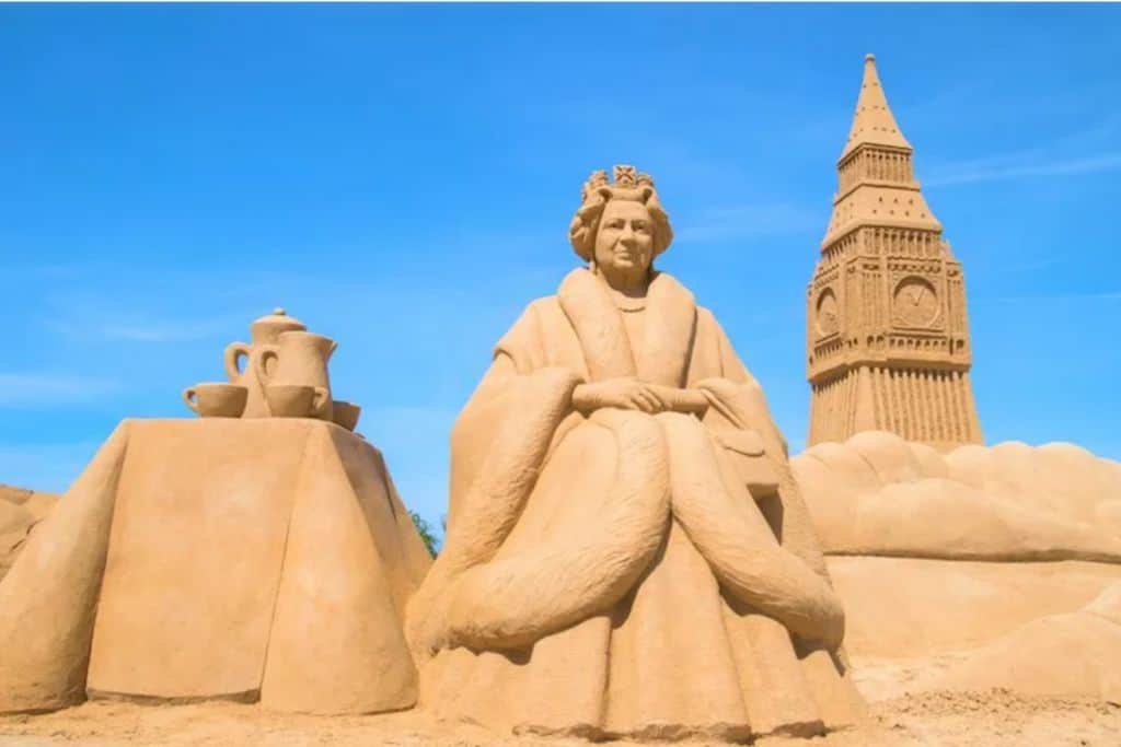 The image is of sand scultpures and there is one very large on of the Queen of England and on her right is Big Ben and on her left is a table with a teapot and cup on it.  This is one of the best things to do in the Algarve with kids. 