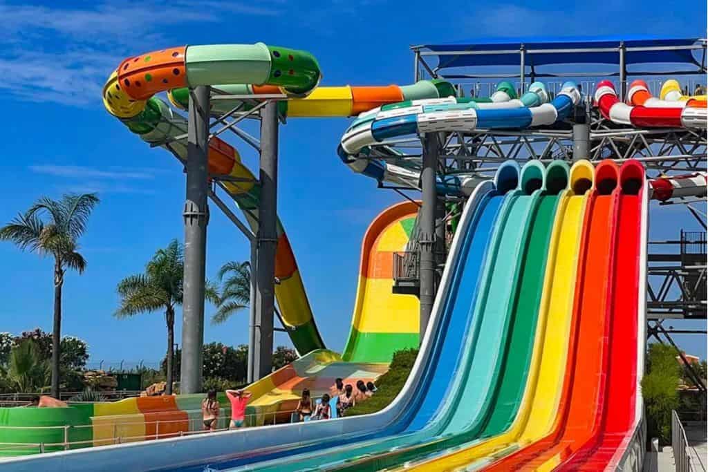 This is a waterpark. There are 5 slides next to eachother in the colour of a rainbow with a big drop going into a pool. This is Slide and Splash water park in the Algarve. 