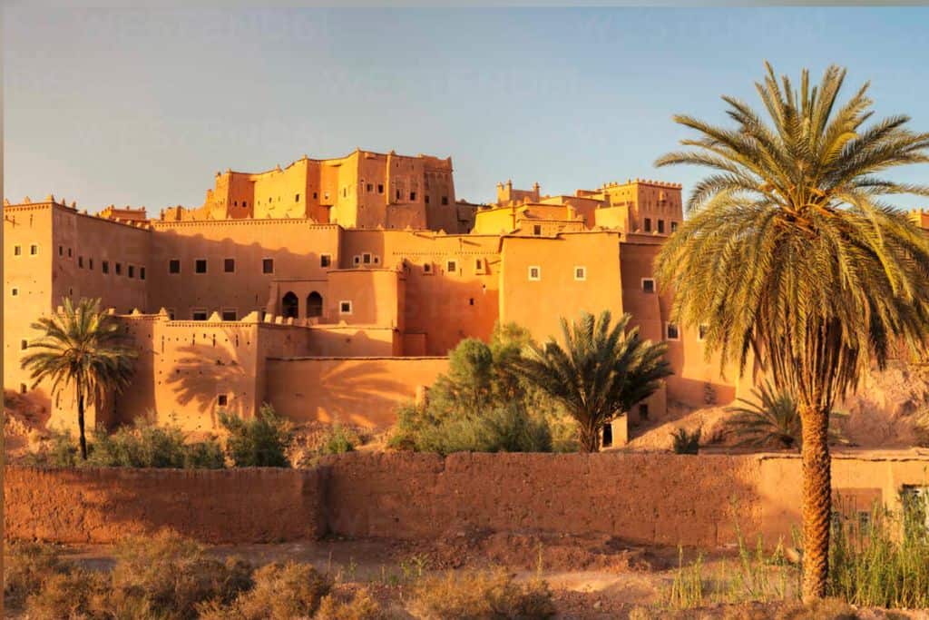 A golden hour image of the kasbah at Taourirt in Morocco.  It is  a collection of earth buildings.