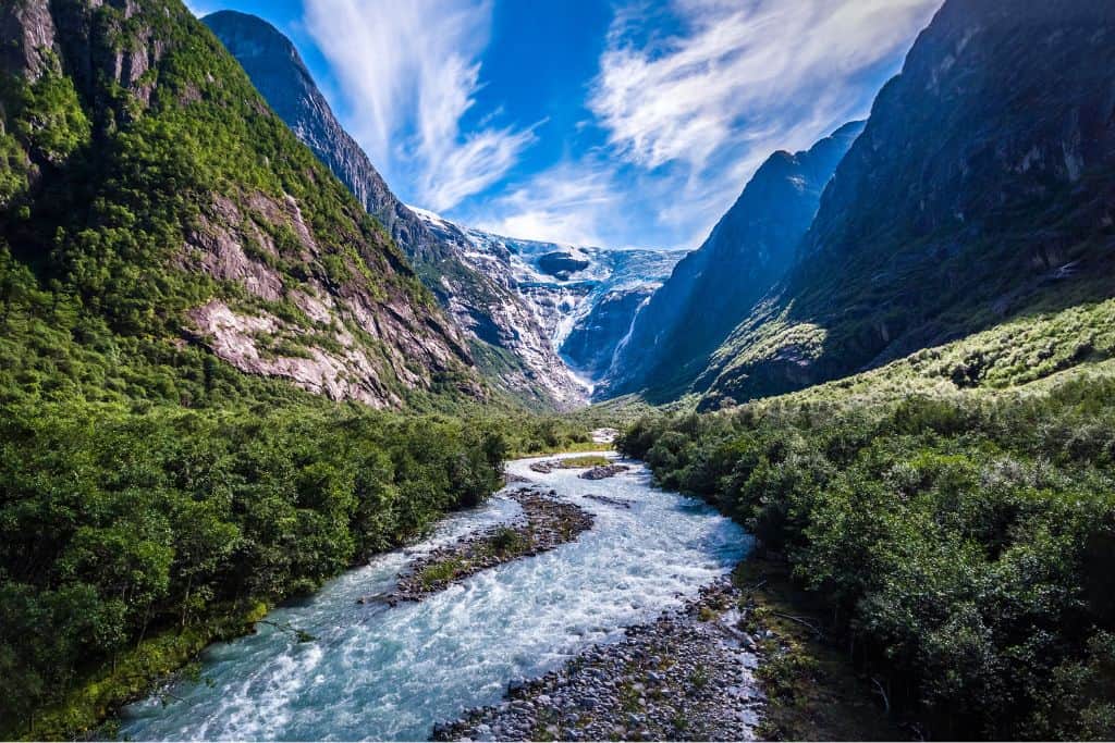 This is a panoramic image of the Kjenndalsbreen Glacier near to Loen in Norway. In the foreground is a small river and then behind that is a mountain with the glacier coming down from it.