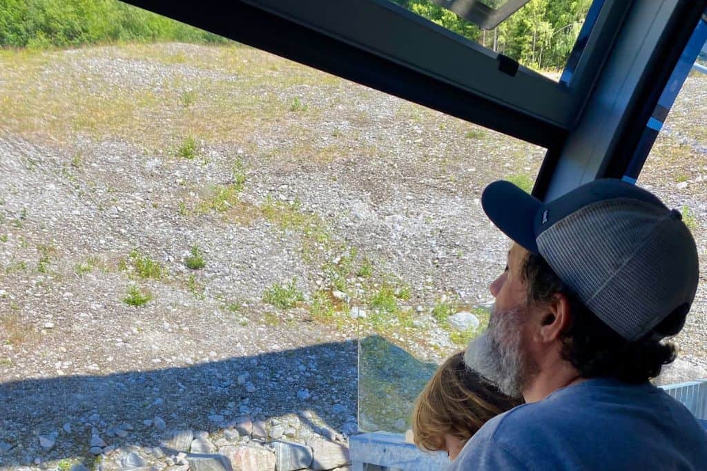 This is the image of the back of the heads of a man and a boy who are looking out of the window of a gondola as it goes up a mountain. This is the Loen Skylift.