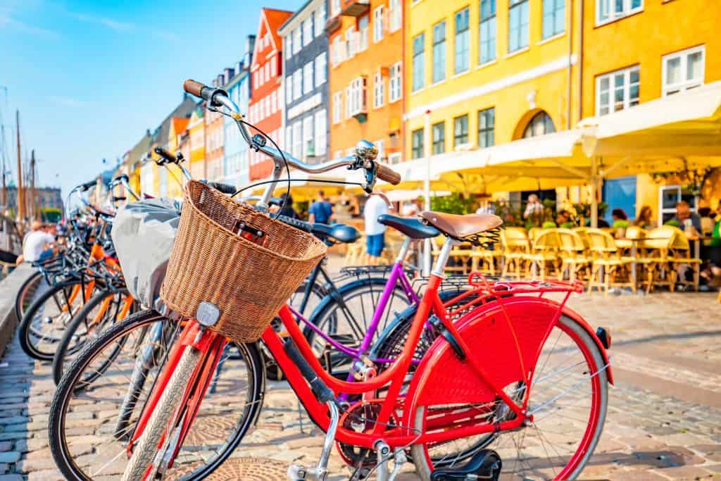 A row of colourful bikes all lined up next to each other. The bikes are in front of the colourful waterfront building in Nyhavn.
Bikes are a great way of exploring Copenhagen with kids.