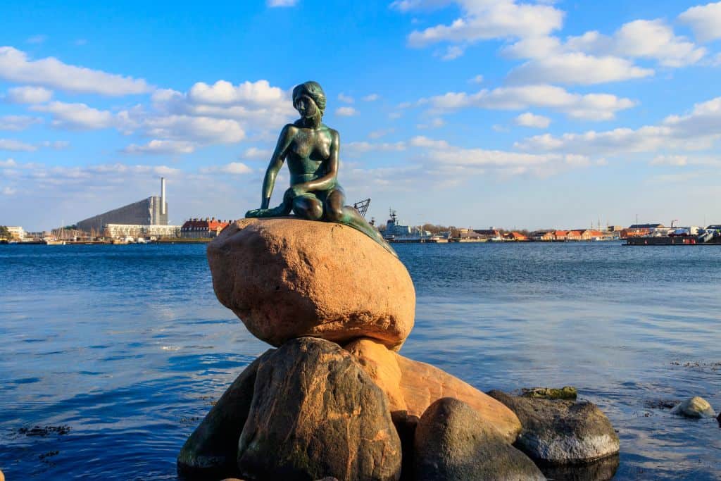 A photo taken of the Little Mermaid statue in Copenhagen.  It's a mermaid on a rock on the edge of the water. This is one of the most popular things to do in Copenhagen with kids